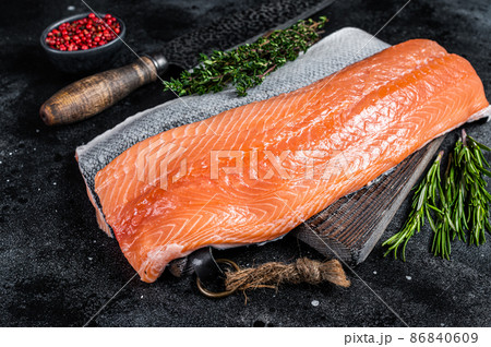Fresh raw salmon fillet fish on cutting board with knife. Black background. Top view 86840609