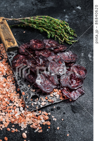 Dry horse salami sausage on a butcher table. Black background. Top view 86840620