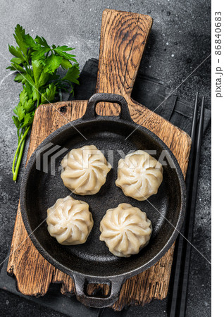 Dim sum stuffed meat dumplings in a pan with herbs. Black background. Top view 86840683