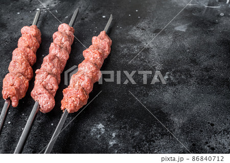 Raw mince lamb meat shish kebab on butcher table. Black background. Top view. Copy space Raw mince lamb meat shish kebab on butcher table. Black background. Top view. Copy space 86840712