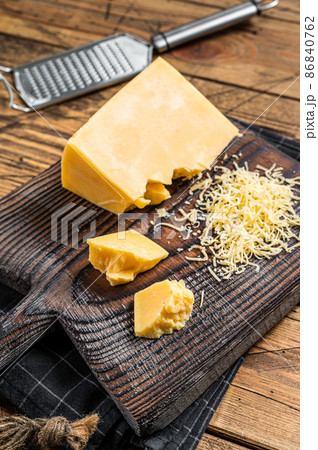 Grated cheddar cheese piece on a wooden board. Wooden background. Top view Grated cheddar cheese piece on a wooden board. Wooden background. Top view 86840762