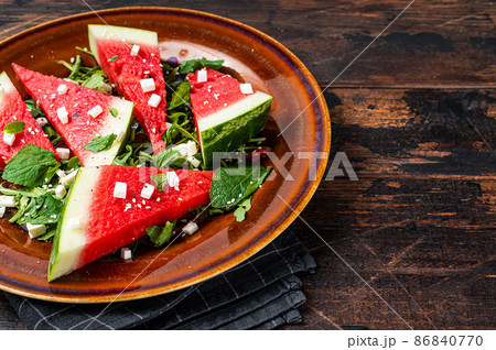 Fresh summer watermelon salad with feta cheese, arugula, onions in a rustic plate. Dark background. Top view. Copy space 86840770