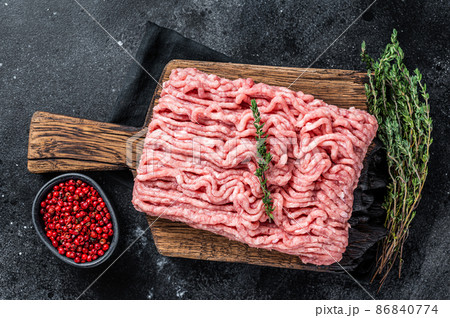 Ground chicken or turkey raw meat on wooden board. Black background. Top View 86840774