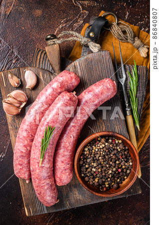 Bratwurst Raw meat sausages on wooden board with spices. Dark background. Top view 86840807