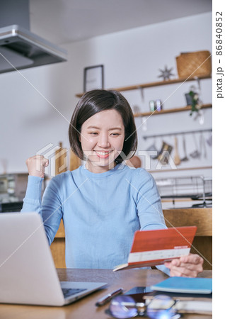 預金通帳を見てガッツポーズをする若い女性 86840852