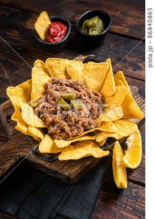 Mexican Baked nachos with chili con carne in a skillet. Wooden background. Top view Mexican Baked nachos with chili con carne in a skillet. Wooden background. Top view 86840865