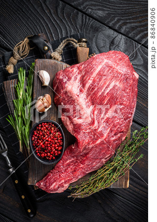 Tri Tip black angus beef steak on cutting board with herbs, raw meat. Black Wooden background. Top view Tri Tip black angus beef steak on cutting board with herbs, raw meat. Black Wooden background. Top view 86840906