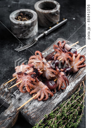 Skewers with Grilled baby mini octopuses. Black background. Top view Skewers with Grilled baby mini octopuses. Black background. Top view 86841056