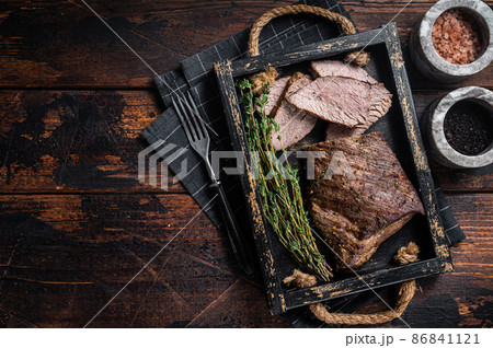 Grilled Tri Tip steak, sirloin bottom beef in a tray with herbs. Wooden background. Top view. Copy space Grilled Tri Tip steak, sirloin bottom beef in a tray with herbs. Wooden background. Top view. Copy space 86841121