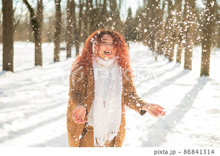 Fat caucasian woman playing snowballs in the park.  86841314