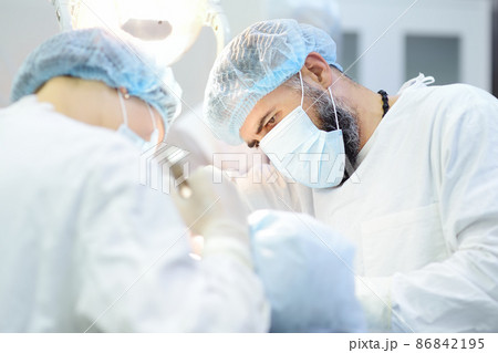 Surgeon and nurse during a dental operation. Anesthetized patient in the operating room. Installation of dental implants in the clinic. Surgeon and nurse during a dental operation. Anesthetized patient in the operating room. Installation of dental implants in the clinic. 86842195