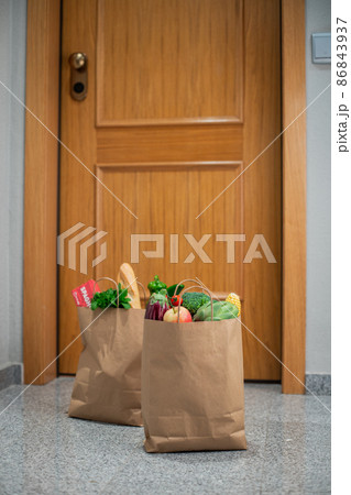 Food shopping bags stand at the door of the house or apartment. Vegetables and fruits delivery during quarantine and self-isolation. 86843937