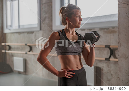 Sporty female athlete lifting dumbbell in gym Sporty female athlete lifting dumbbell in gym 86844090