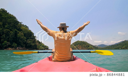 Man with thin plait hairstyle rows pink plastic kayak putting up Man with thin plait hairstyle rows pink plastic kayak putting up 86844881