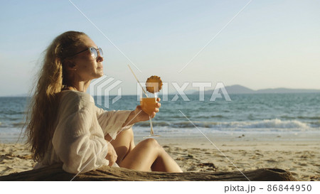 Woman sitting in white dress drinks pineapple cocktail Pina Cola Woman sitting in white dress drinks pineapple cocktail Pina Cola 86844950