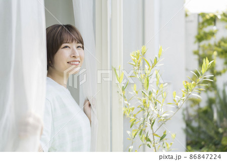 カーテンを開けて外を見る笑顔の20代の女性 ポートレート カーテンを開けて外を見る笑顔の20代の女性 ポートレート 86847224