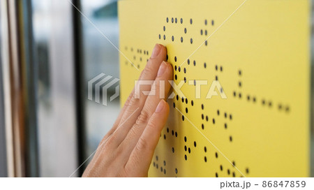 Close-up of a woman reading a braille lettering on a glass door. Close-up of a woman reading a braille lettering on a glass door. 86847859