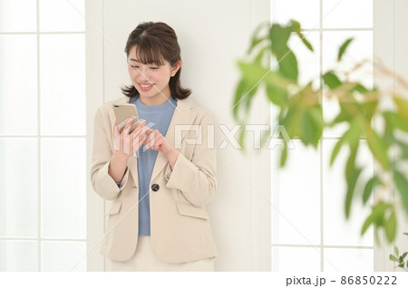 部屋でスマホを操作する若い女性 86850222