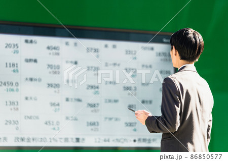株価ボードを見る男性（スマートフォンを手に持つ） 86850577