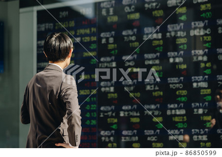 株価ボードを見る男性（スマートフォンを手に持つ） 86850599