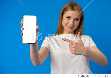 Young woman point finger at isolated smartphone screen over blue color background 86852015