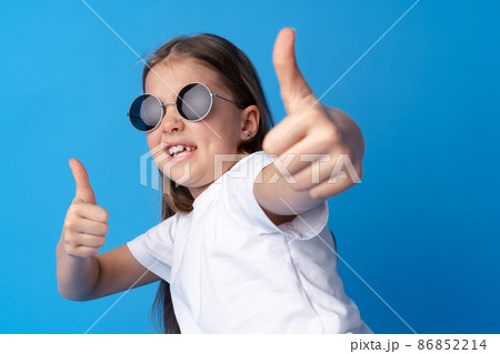 Portrait of teen girl making thumb up gesture on blue background Portrait of teen girl making thumb up gesture on blue background 86852214