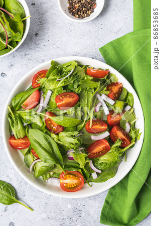 Summer green salad in white bowl plate on grey table Summer green salad in white bowl plate on grey table 86853685