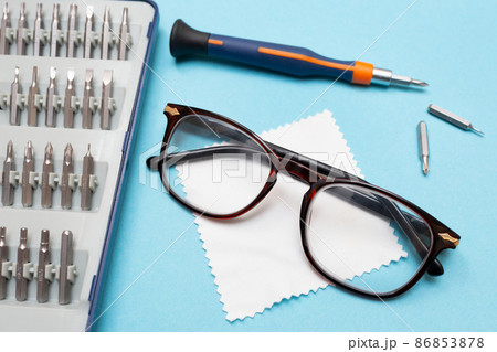 Repair of glasses. Glasses and a screwdriver on a blue background. Eyewear repair tools and accessories. Repair of glasses. Glasses and a screwdriver on a blue background. Eyewear repair tools and accessories. 86853878