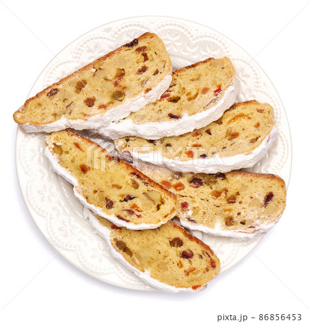 Slices of Traditional Christmas stollen cake with marzipan and dried fruit isolated on white ceramic palte Slices of Traditional Christmas stollen cake with marzipan and dried fruit isolated on white ceramic palte 86856453
