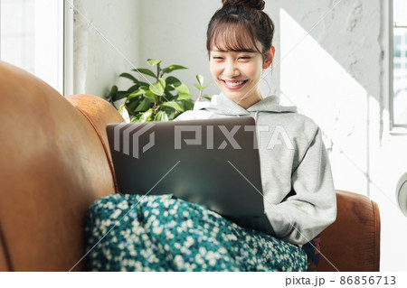 自宅のソファーでパソコンを使う女性 自宅のソファーでパソコンを使う女性 86856713