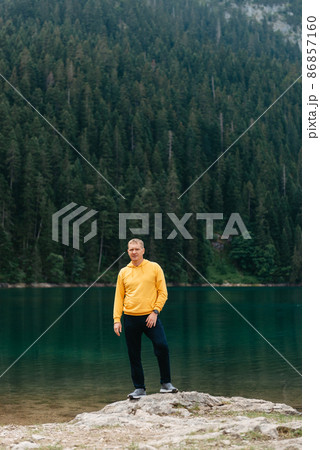 Traveler Man relaxing meditation with serene view mountains and lake landscape. Travel Lifestyle hiking concept summer vacations outdoor. Guy standing near the mountain Lake. A lonely man looks ahead Traveler Man relaxing meditation with serene view mountains and lake landscape. Travel Lifestyle hiking concept summer vacations outdoor. Guy standing near the mountain Lake. A lonely man looks ahead 86857160