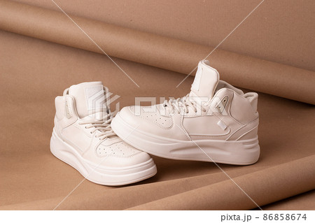 Eco leather shoes. A pair of beige sneakers on brown background. Minimal style. Casual sport lifestyle concept Eco leather shoes. A pair of beige sneakers on brown background. Minimal style. Casual sport lifestyle concept 86858674