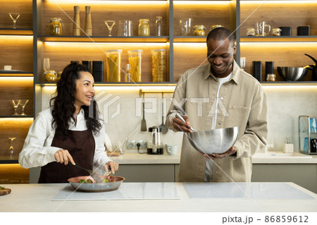 Young multiracial couple cooks dinner together in kitchen Young multiracial couple cooks dinner together in kitchen 86859612