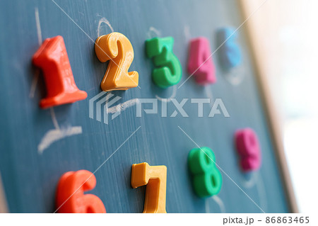 Learning numbers on a blackboard with colorful magnets and handwriting on blackboard during homeschooling at quarantine Learning numbers on a blackboard with colorful magnets and handwriting on blackboard during homeschooling at quarantine 86863465