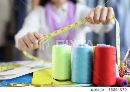 On the table of a seamstress are colored bobbins with threads On the table of a seamstress are colored bobbins with threads 86864379
