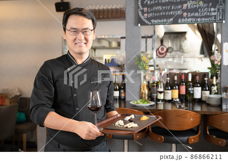 飲食店でワインと料理を提供する男性スタッフ 飲食店でワインと料理を提供する男性スタッフ 86866211