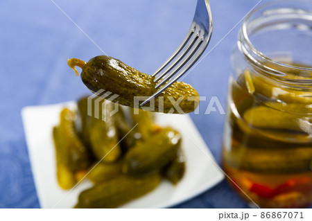 One pickled cucumber on fork, homemade preserves 86867071