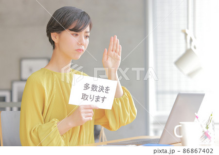 多数決を取りますのフリップを持ち真剣な表情でミーティングを仕切る女性2 86867402