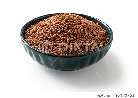 Raw wholegrain buckwheat groats in a blue bowl isolated on a white background. 86870753