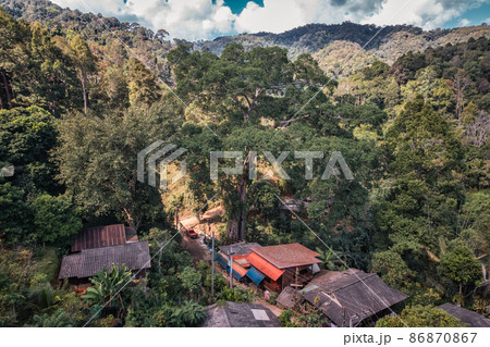 Aerial view of traditional rural village of tribe local people with large tree in tropical rainforest on countryside at national park 86870867