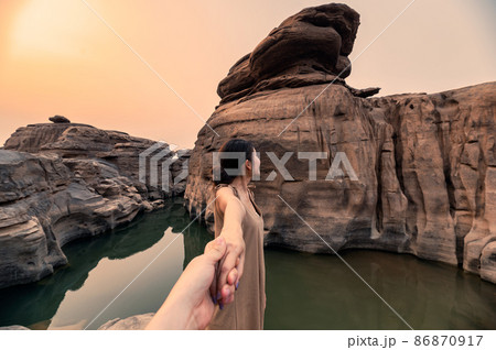 Asian woman holding hands with couple in rock gorge of grand canyon at evening Asian woman holding hands with couple in rock gorge of grand canyon at evening 86870917