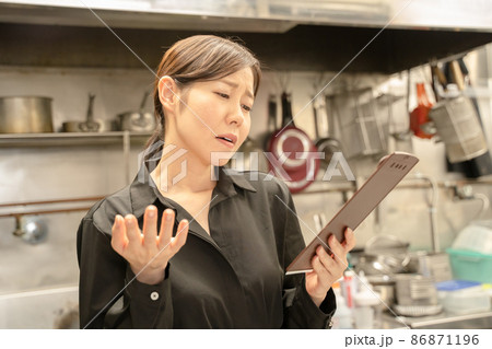 飲食店で伝票確認し困る女性スタッフ 86871196