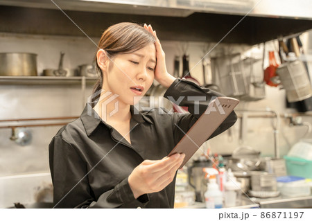 飲食店で伝票確認し困る女性スタッフ 86871197