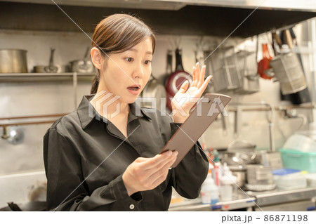 飲食店で伝票確認し驚く女性スタッフ 86871198