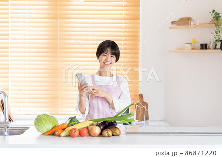 キッチンでスマホを操作する若い女性 キッチンでスマホを操作する若い女性 86871220