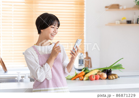 キッチンでスマホを操作する若い女性 86871229