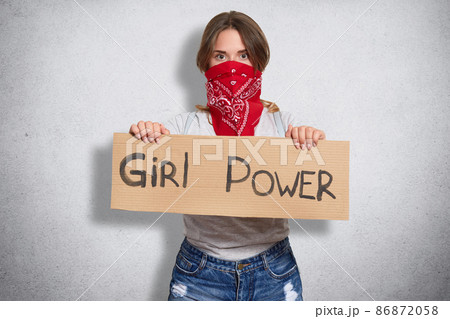 Active powerful cute young female looking directly at camera, showing inscription girl power, curious about social problems, uniting like minded people, isolated over grey background in studio. 86872058