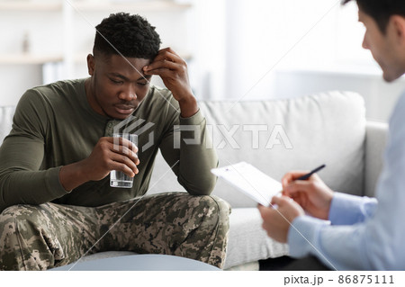 Emotional black military man drinking water while talking to psychotherapist Emotional black military man drinking water while talking to psychotherapist 86875111