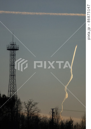 Air plane traces on the sunset sky. Tree silhouettes background 86875147