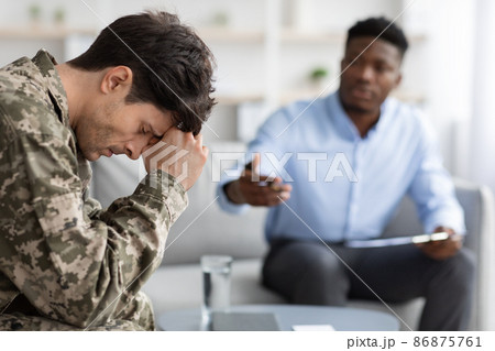 Distressed young man soldier attending therapy session with psychiatrist Distressed young man soldier attending therapy session with psychiatrist 86875761
